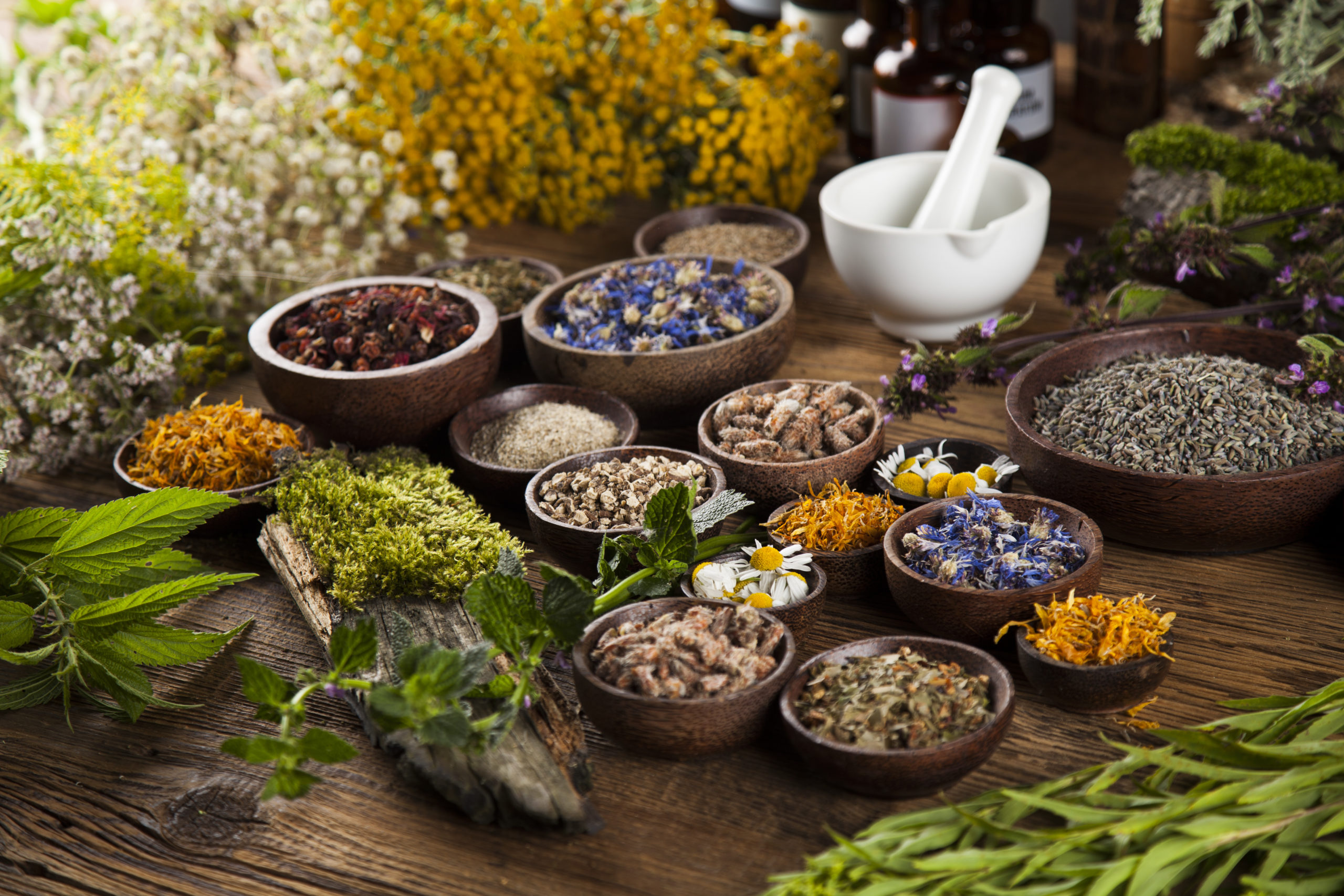 An assortment of herbs and natural remedies displayed on a wooden table, representing the use of herbal medicine in holistic health practices.
